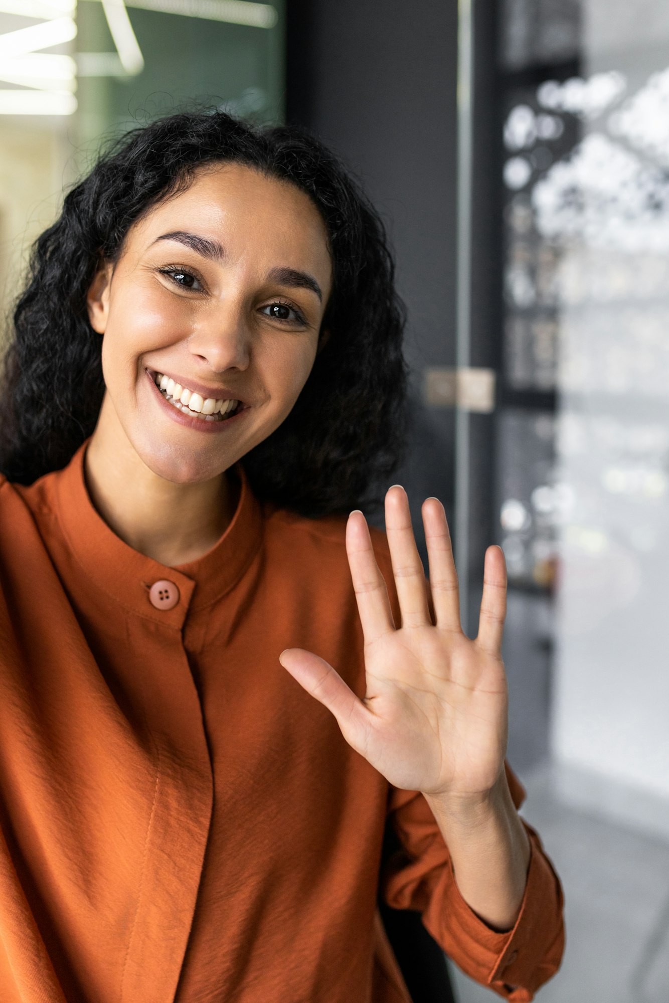 Vertical shot, young beautiful Hispanic business woman with curly hair talking on video call