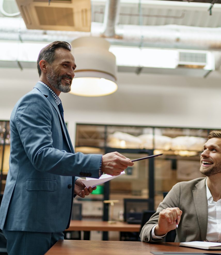 Mature business coach or speaker make flip chart presentation to diverse businesspeople at meeting